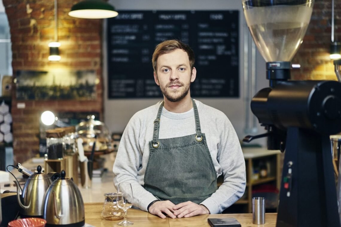 portrait-of-young-male-barista-at-coffee-shop-kitchen-counter.jpg